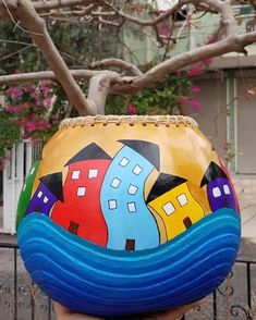 a person holding up a painted ball in front of a tree