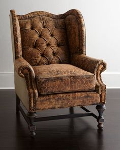 an old leather chair sitting on top of a hard wood floor next to a white wall