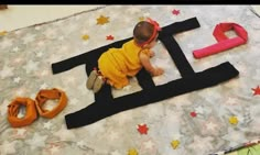 a baby is laying on the floor next to letters made out of paper and scissors