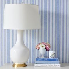 a white lamp sitting on top of a table next to a blue and white striped wall