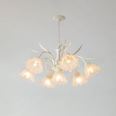 a white chandelier with flowers hanging from it's center and four lights on each side