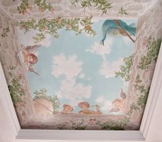 the ceiling is painted with flowers and angels on it's sides, as well as a blue bird flying overhead