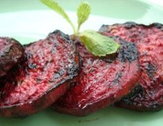 grilled steaks on a white plate with a sprig of green leaf