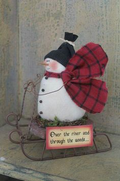 a snowman sitting on top of a sled with a sign saying over the river and through the woods