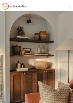 a living room filled with lots of furniture next to a wall mounted shelf covered in vases