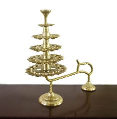 a golden metal candle holder on top of a wooden table