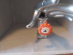 an animal keychain hanging from the side of a metal object with a lion face on it