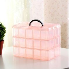 a pink plastic storage box sitting on top of a table next to a potted plant