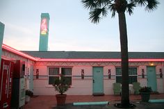 the motel is lit up with neon lights and palm trees in front of its building