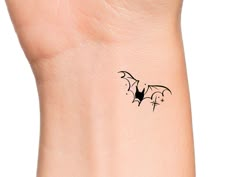 a small black bat tattoo on the wrist