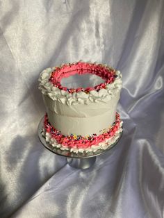 a white cake with pink frosting and sprinkles