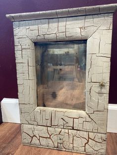 an old wooden frame sitting on top of a hard wood floor next to a purple wall