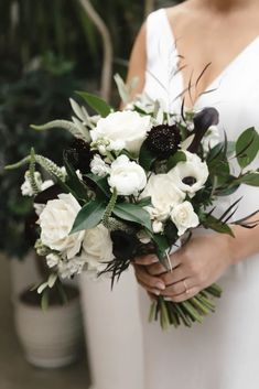 a bride holding a bouquet of white and black flowers