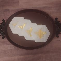 three bees are sitting on top of a plate that is decorated with white and gold foil