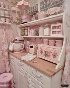 a pink and white kitchen with lots of dishes