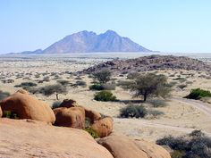 an elephant standing on top of a large rock in the middle of a dirt field