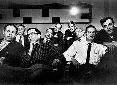 a group of men sitting next to each other in front of a tv screen with one man holding his chin up