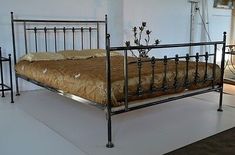 a metal bed frame with an iron headboard and foot board, in a white room