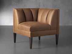 a tan leather chair sitting on top of a gray floor