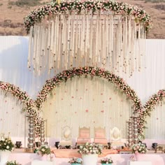 an outdoor ceremony setup with flowers and greenery on the wall, decorated in white and pink colors