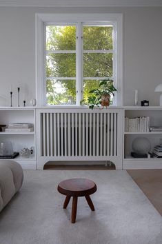 a living room filled with furniture and a large window above the couches is a radiator