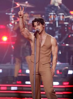 a male singer is performing on stage with his hands in the air and one hand up