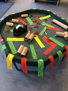 a green table topped with lots of crafting supplies on top of a wooden floor