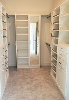 an empty walk in closet with white shelving and drawers on both sides, open doors to the other side