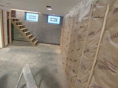 an unfinished room with stairs and walls covered in tarp next to a wall that is being built