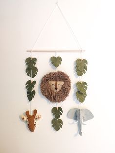 a wall hanging with various animal heads on it's sides and leaves attached to the hooks