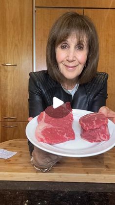 a woman holding a plate with raw meat on it