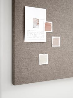 a bulletin board with several different shades of paint on it and some papers pinned to the wall