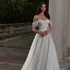 a woman in a white wedding dress posing for the camera with her hands on her hips