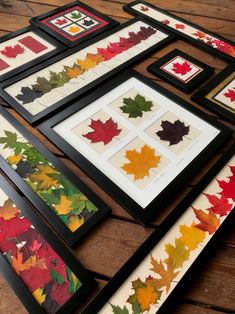 some framed pictures with leaves on them sitting on a wooden table next to each other