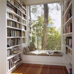 a window seat in the corner of a room with bookshelves full of books