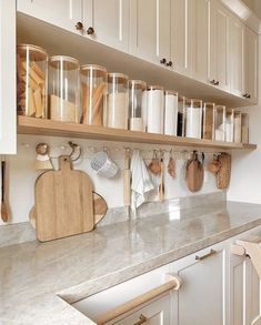 a kitchen with white cabinets and wooden utensils hanging on the wall above the counter