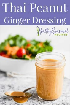 a jar filled with ginger dressing next to a bowl of salad