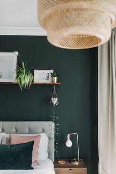 a bedroom with dark green walls, white bedding and plants on the nightstands