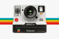 an old polaroid camera sitting on top of a tripod in front of a rainbow striped background