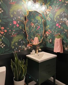 a bathroom with a sink and mirror next to a toilet covered in wallpapers