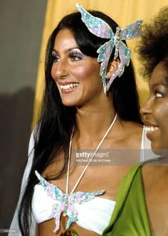 two beautiful women standing next to each other wearing butterfly headpieces on their heads