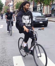 a man with dreadlocks riding a bike down the street