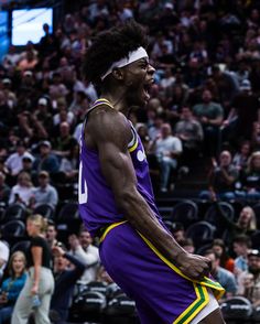 a male basketball player in a purple uniform and fans are watching him from the sidelines