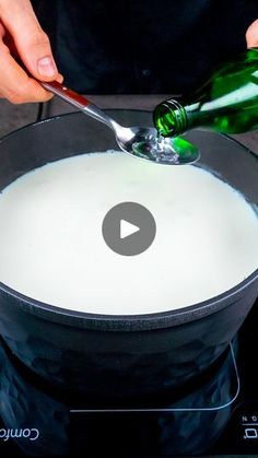 a person pouring milk into a pan with a bottle in it and a spoon sticking out