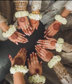 several people holding their hands together in the middle of a circle with flowers all over them