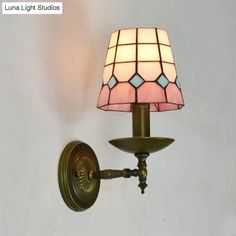 a wall light with a stained glass shade on it's arm and the bulb turned off