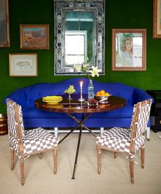 a blue couch sitting next to a table with two chairs and a vase on it