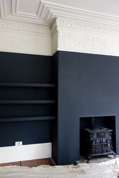 an empty room with a fireplace in the middle and dark blue paint on the walls