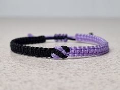 a purple and black bracelet on a white surface