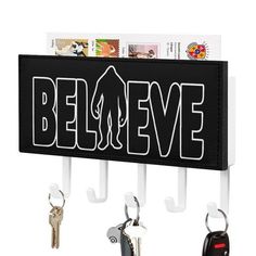 a black and white sign that says believe with keys hanging from it's hooks